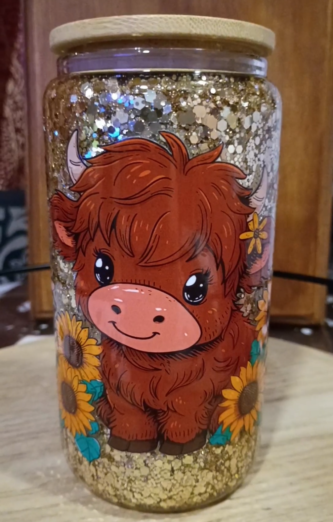Custom Highland Cow Glitter Snow Globe Tumbler with gold glitter, baby cow, sunflowers, and bamboo lid